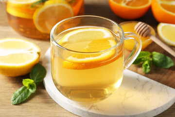 Aromatic fruit tea in glass cup, orange, lemon, honey and mint on wooden table, closeup