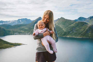 Baby and mom family traveling in Norway mother and child hiking together outdoor, woman parent with infant kid walking in mountains above fjord summer vacations trip, Mothers day holiday