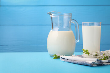 Fresh milk and blossoms on light blue table, closeup. Space for text
