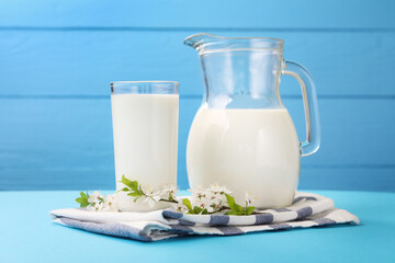 Fresh milk and blossoms on light blue table, closeup