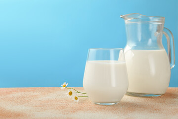 Fresh milk and flowers on table against light blue background, closeup. Space for text