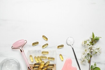 Flat lay composition with collagen capsules and blossoms on white marble table