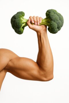 Naklejki A muscular male arm holds a dumbbell made from two broccoli heads connected by a stalk.