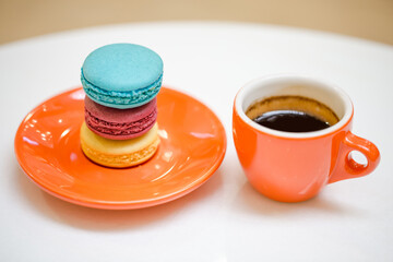 Colorful macarons with orange coffee cup