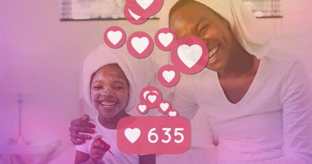 Image of heart reactions over happy african american mother and daughter during skin care