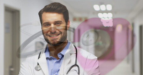 Image of stethoscope over happy caucasian male doctor in hospital