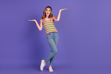 Smiling young woman in colorful striped top gesturing on a vibrant purple background