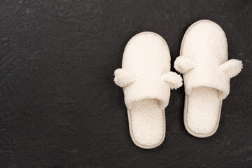 Soft teddy slippers on concrete background, top view