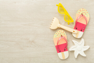 Children's flip flops and beach toys on wooden background,,top view