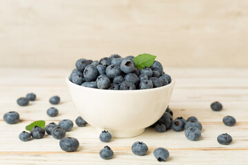 Bowl with fresh blueberries on wooden table