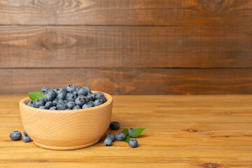 Bowl with fresh blueberries on wooden table
