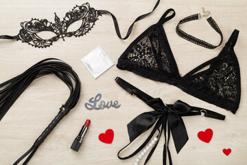 Set of erotic BDSM accessories on wooden background, top view
