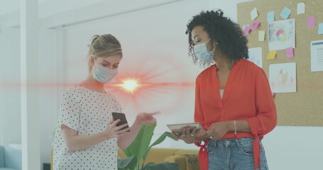 Image of data processing over businesswomen wearing face masks