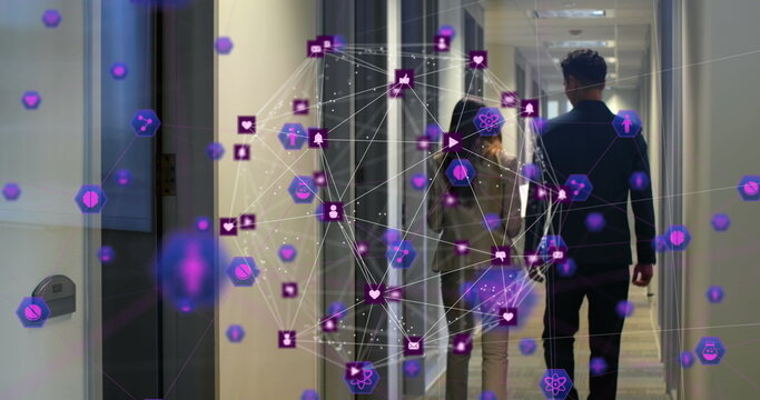 Image of network of connections with icons over back view of diverse businesspeople in office