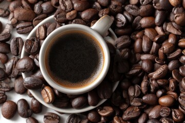 Fototapeta premium Aromatic coffee cup filled with dark espresso rests amongst roasted coffee beans, creating a close-up still life with rich, warm textures and inviting tones.