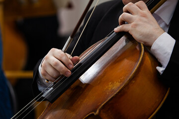 A fragment of a cello in the hands of a musician in an orchestra