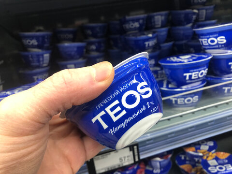 A customer holds a drinking fruit yogurt Teos in his hand in a supermarket.
