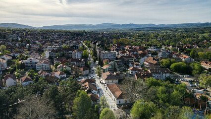 Obraz premium A mesmerizing aerial view of Sokobanja, Serbia, at sunset. The soft golden glow highlights the town and hills, merging urban life with nature’s splendor.