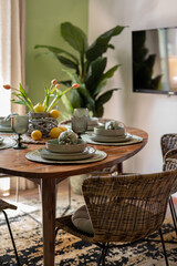 Cozy dining table setting with woven chairs and a rustic wooden table in natural light
