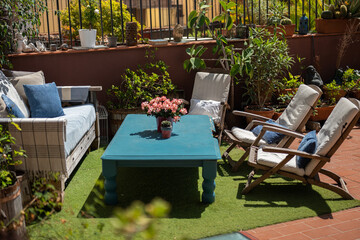 Cozy outdoor lounge with wooden furniture, lush plants, and a blue rustic coffee table