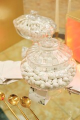 A Glass Jar Filled With White Candies Sitting On Top Of A T