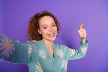 Young Woman in Stylish Cardigan Smiling Cheerfully and Giving a Thumbs Up Gesture Against a Vibrant...