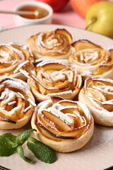 Tasty apple roses with powdered sugar served on table, closeup