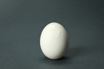 One egg with cracked shell on grey background, closeup