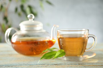 Freshly brewed tea in glass cup and teapot on wooden table