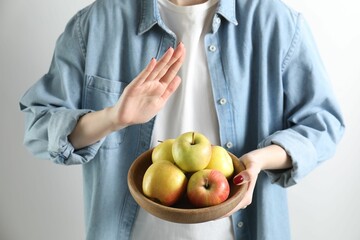Woman refusing to eat apples on white background, closeup. Food allergy concept