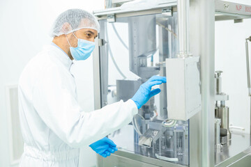 Naklejka premium The technician carefully adjusts the settings on a pharmaceutical machine to ensure proper functioning in the production line.