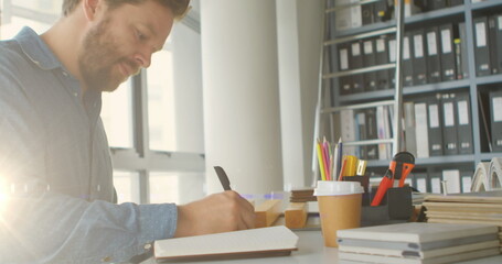 Image of light over caucsaian man writing in notebook