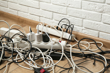 Extension power boards overloaded with plugs on wooden floor, closeup