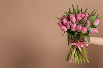 Woman with bouquet of beautiful tulips on dark beige background, closeup. Space for text