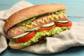 Tasty hot dog with vegetables on blue wooden table, closeup