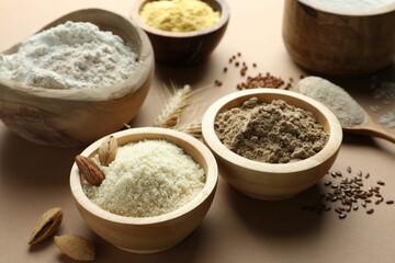 Different types of flour on light brown table, closeup