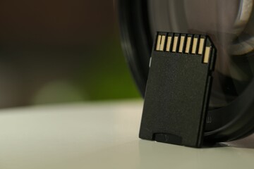 SD memory card and photo camera on white table, closeup. Space for text