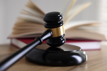 Judge's gavel and books on wooden table indoors, selective focus
