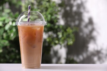 Tasty iced coffee on white table against blurred background. Space for text