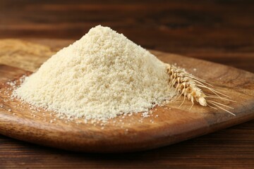 Pile of flour and spike on wooden table, closeup
