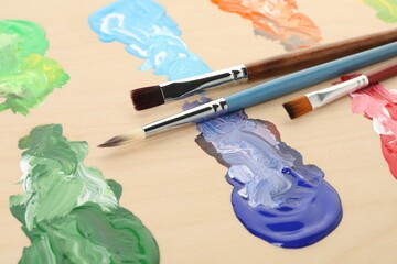 Wooden palette with paints and brushes, closeup
