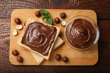 Toast with tasty chocolate hazelnut spread, nuts and mint on wooden table, flat lay