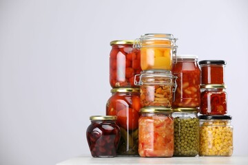 Many jars with different pickled products on light grey table, space for text