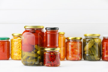 Many jars with different pickled products on white wooden table