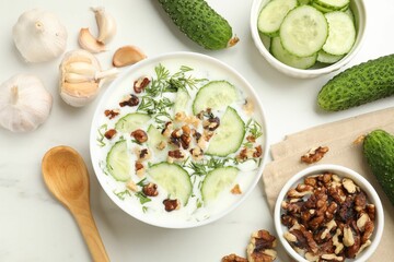 Tasty cucumber soup with dill, nuts and garlic on white table, flat lay