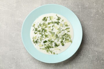 Tasty cucumber soup with dill on grey textured table, top view