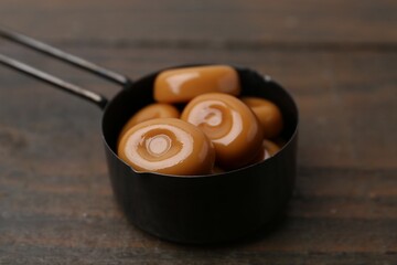 Tasty sweet caramel candies on wooden table, closeup
