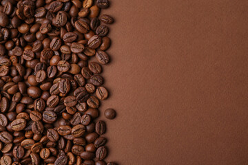 Aromatic coffee beans on brown background, top view. Space for text