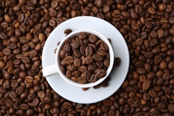 Cup and saucer on coffee beans, top view