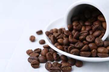 Aromatic coffee beans, cup and saucer on white table, closeup. Space for text